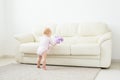 Childhood, babyhood and people concept - happy little baby girl playing near couch at home