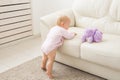 Childhood, babyhood and people concept - happy little baby girl playing near couch at home