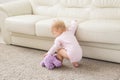 Childhood, babyhood and people concept - happy little baby girl playing near couch at home