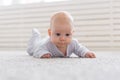 Childhood, babyhood and people concept - little baby boy or girl crawling on floor at home Royalty Free Stock Photo