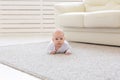 Childhood, babyhood and people concept - little baby boy or girl crawling on floor at home Royalty Free Stock Photo