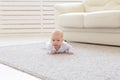 Childhood, babyhood and people concept - little baby boy or girl crawling on floor at home Royalty Free Stock Photo