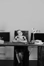 Childhood and back to school concept. Girl sits at desk with colorful stationery, flowers and fruit Royalty Free Stock Photo