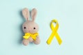 Childhood Cancer Awareness Golden Ribbon with toy bunny on blue background Royalty Free Stock Photo