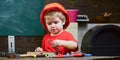 Childhood concept. Boy play as builder or repairer, work with tools. Kid boy in orange hard hat or helmet, study room Royalty Free Stock Photo