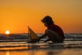 Childhood concept. Kid boy holding tou boat. Cute little blond boy put toy boat in the sea water waves at the beach on Royalty Free Stock Photo