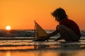 Childhood concept. Kid boy holding tou boat. Cute little blond boy put toy boat in the sea. Dream on travel. Sea dream Royalty Free Stock Photo