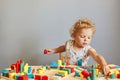 Childhood curiosity and discovery. Playful games for curious minds. Cute creative wavy haired blonde toddler baby playing wooden