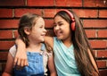 Childhood days are full of fun. two young girls standing against a brick wall. Royalty Free Stock Photo