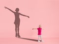 Childhood and dream about big and famous future. Conceptual image with girl and shadow of fit female figure skater on Royalty Free Stock Photo