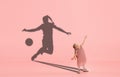 Childhood and dream about big and famous future. Conceptual image with girl and shadow of fit female football player on