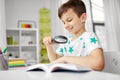 Boy with magnifier reading book at home