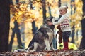 Childhood, game and fun. Little girl with dog in autumn forest. Activity and active rest. Red riding hood with wolf in