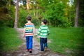 Childhood, hiking, family, friendship and people concept - two happy kids walking along forest path Royalty Free Stock Photo