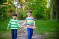 Childhood, hiking, family, friendship and people concept - two happy kids walking along forest path Royalty Free Stock Photo