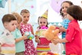 Childhood, holidays, celebration and friendship concept. Happy kids giving gifts at birthday party