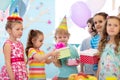 Childhood, holidays, celebration and friendship concept. Happy children in party hats giving gifts at birthday party Royalty Free Stock Photo