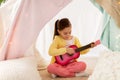 Girl playing toy guitar in kids tent at home Royalty Free Stock Photo