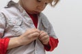 Childhood independence concept ,little boy buttoning on shirt, fastening his buttons , isolated on white gray background Royalty Free Stock Photo