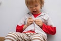 Childhood independence concept ,little boy buttoning on shirt, fastening his buttons , on white gray background. The Royalty Free Stock Photo