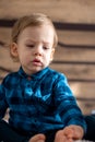 Childhood, infant, minor concepts - close up one blonde black-eyed sad, offended child baby boy on soft powdery bed in