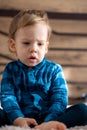 Childhood, infant, minor concepts - close up one blonde black-eyed sad, offended child baby boy on soft powdery bed in