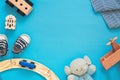 Childhood layout on blue background, cute wooden baby toys and toddler`s first shoes, free space, place for text Royalty Free Stock Photo