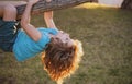 Childhood leisure and kids activities concept. Child hanging upside down on tree and having fun in summer park.