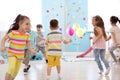 Childhood, leisure and people concept - group of happy kids playing tag game and running in spacious room