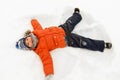 Happy little boy making snow angels in winter Royalty Free Stock Photo