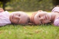 Childhood moments. Two little girl lying happily on the grass and laughing. Royalty Free Stock Photo