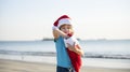 Childhood and New Year. Cute baby boy in red Santa hat with christmas stocking on sunny winter day on sea. Royalty Free Stock Photo