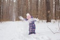Childhood and people concept - child girl walking in the winter outdoors and throwing the snow up
