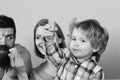 Childhood and playing concept. Man with beard, woman and boy play on blue background.. Family with curious faces spend Royalty Free Stock Photo