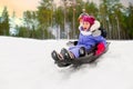 kids sliding on sled down snow hill in winter Royalty Free Stock Photo