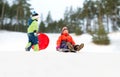 happy kids sliding on sleds down hill in winter Royalty Free Stock Photo