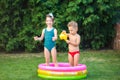Childhood summer games with water pool. Caucasian brother and sister play with plastic toys watering can pouring water splashing, Royalty Free Stock Photo