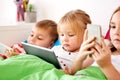 Little kids with tablet pc in bed at home Royalty Free Stock Photo