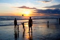 Children and adults play ball on the beach during sunset