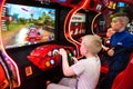 Children and adults play on the slot machines, attractions in the shopping center. Families with children have fun and play arcade