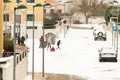 Children and adults play in the snow on a snowy and foggy street in an urbanization during a cold winter day in Zamora, Spain.