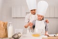 children in aprons and chef hats whisking eggs in bowl at table Royalty Free Stock Photo