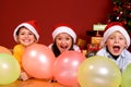 Children with ballons by Christmas tree