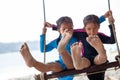 Children bare feet with sand while they playing on a swings together at the beach near the sea in vacation Royalty Free Stock Photo