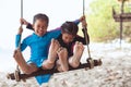 Children bare feet with sand while they playing on a swings together at the beach near the sea in vacation Royalty Free Stock Photo