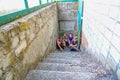 Children in the basement, three boys and a girl near the iron door are hiding on the steps from the outside world. Post-production Royalty Free Stock Photo