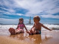 Children on the beach: A boy and a girl in funny sunglasses are sitting on the seashore in sea foam. In the background a Royalty Free Stock Photo