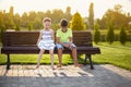 Children best friends boy and girl sitting on bench in park. children smiling looking at shadows of their legs , sunny Royalty Free Stock Photo