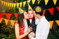 Children birthday party. Family father and mother hold son of one year of birth in arms and kiss cheekin the background of park an