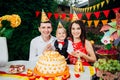 Children birthday theme. family of three Caucasian people sitting in backyard of the house at a festive decorated table in funny h